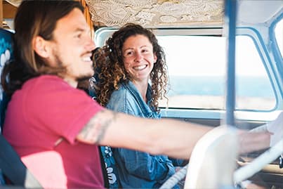 Happy couple driving in campervan by the coast